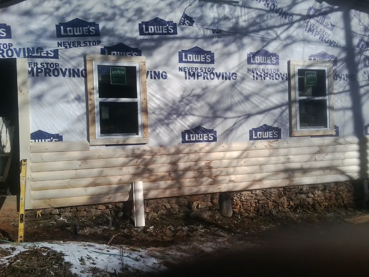 House wrap and new log siding going up on an exterior wall in Hoschton