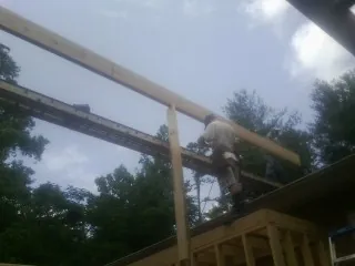 Carpenter setting a ridge beam over a new addition frame — Ice Dam Removal by Roofing Brothers in Hoschton