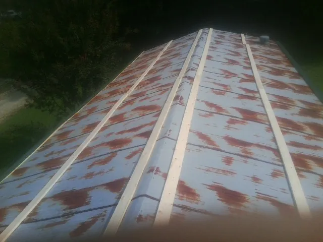 Rusted metal roof panels with new wood purlins before replacement — Storm Damage Roof Repair in Hoschton by Roofing Brothers