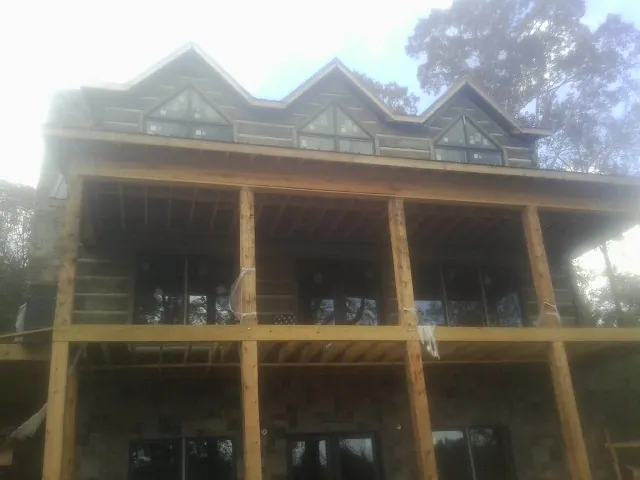 Dormers and porch framing on a large log home under construction — Roof Coating work by our crew in Hoschton