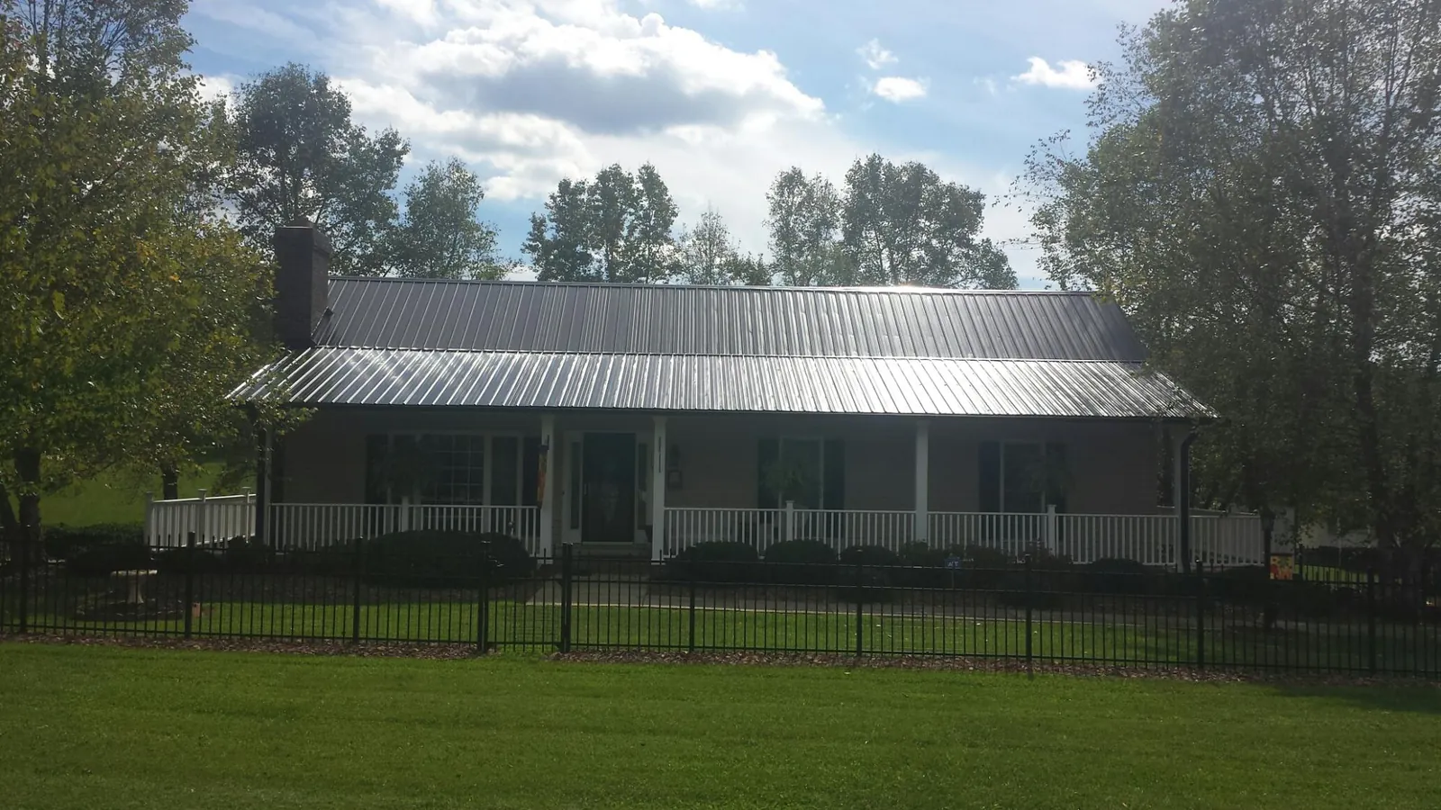 Gray metal roof on a brick ranch with a full width front porch — Gutter Guard Installation work by our crew in Hoschton