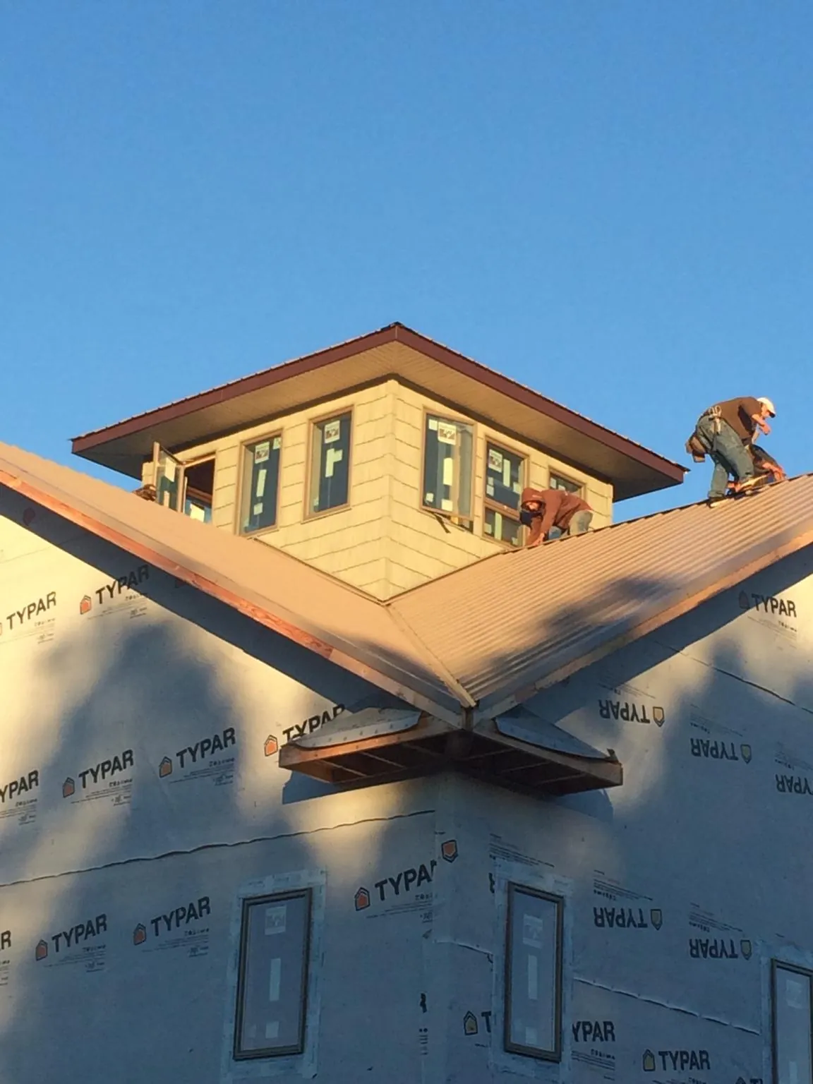 Roofers working around a rooftop cupola on a new metal roof at sunset — Roof Waterproofing in Hoschton by Roofing Brothers